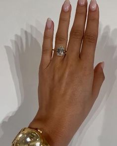 a woman's hand with two rings on it and a gold bracelet around her wrist