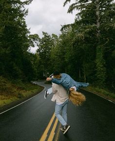 a person riding a skateboard down the middle of a road with trees in the background