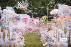 an outdoor wedding setup with flowers and balloons on the back wall, decorated in pastel colors