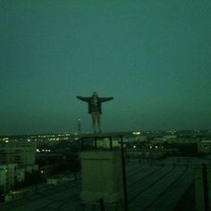 a woman standing on top of a building with her arms outstretched