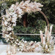 a wedding arch decorated with white flowers and pamodia in front of a pool