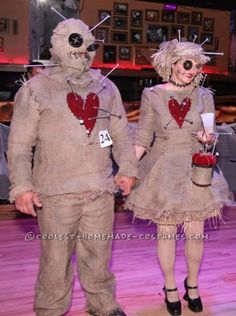 two people dressed up as zombies holding hands and walking on a wooden floor in costume