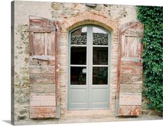 an old stone building with shutters open and green plants growing on the outside wall