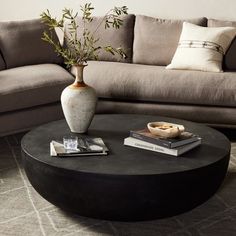 a living room with a couch, coffee table and two vases on the tables