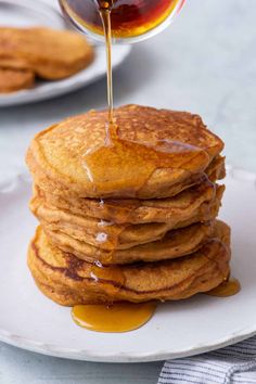 a stack of pancakes with syrup being drizzled on top