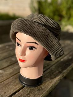 a mannequin head wearing a hat on top of a wooden bench outside in the sun