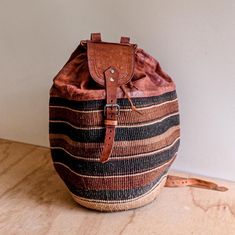 Handwoven African Kiondo raffia/sisal and leather backpack/bucket bag  Lovely authentic hand braided sisal and leather backpack, handmade in Kenya, Central Africa. The bag is a brown and beige colour with black lines and is a generous extra large size.  Can be used as a duffle bag, overnight bag or market bag.  Straps are adjustable. The small leather ring that holds strap belt is missing on one side as shown in last pic. This does not affect use.  Measures: L46 x W34cm Handwoven Brown Leather Bucket Bag, Brown Leather Handwoven Bucket Bag, Handwoven Leather Bucket Bag In Natural Color, Natural Leather Woven Bucket Bag, Artisan Woven Bucket Bag, Brown Handwoven Bucket Bag, Weaving Bucket Bag For Travel, Leather Bucket Bag For Market, Travel Bucket Bag Handwoven