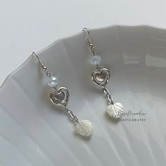 "Handmade Beaded Earrings ✿ Made with glass beads, freshwater pearls, glass crystal beads, and metal accents ✿ Silver, clear milky white, and pearlescent off white ✿ The earrings are 2.9\" long Fish Hook Options ✿ The Titanium fish hook is hypoallergenic and ideal for sensitive skin ✿ The regular fish hook is made of nickel free metal, it is not hypoallergenic" White Beaded Metal Earrings, White Pearl Charm Earrings In Metal, White Metal Dangle Beaded Earrings, Handmade White Metal Pearl Earrings, Handmade White Pearl Earrings With Metal, White Pearl Earrings With Metal Charm, White Heart Beads Drop Earrings, White Drop Earrings With Heart Beads, Nickel-free White Crystal Metal Earrings