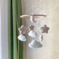 a crocheted mobile with stars and clouds hanging from it's sides in front of a window