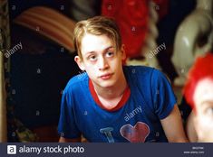 a young boy looking at the camera in front of another man with red hair - stock image