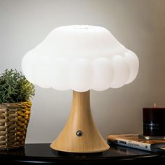 a white lamp sitting on top of a table next to a potted green plant