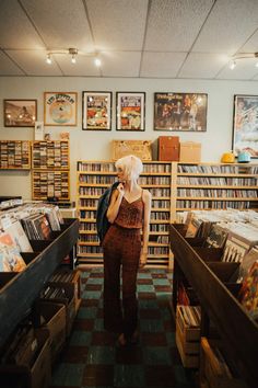 a woman is standing in the middle of a book store looking at her cell phone