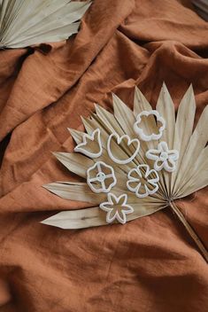 some paper flowers and leaves on a brown cloth