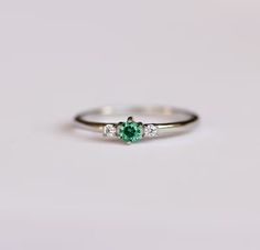 an emerald and diamond three stone ring on a white background with copy space in the middle