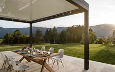 an outdoor dining area with table, chairs and view of the mountains in the distance