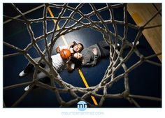 two people laying on the ground in front of a basketball net with their arms around each other