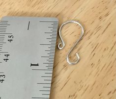 a measuring tape with a metal hook on it next to a piece of paper that has been cut in half