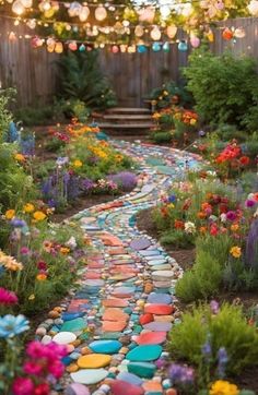 a garden path made out of stones with flowers and lights strung above the walkways