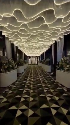 a large room with black and white checkered flooring, chandeliers and flower pots