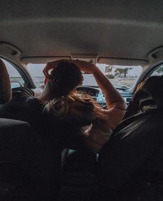 a woman sitting in the back seat of a car with her hand on her head