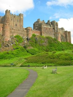 an old castle on top of a hill with a path leading up to the entrance