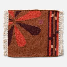 a brown and red rug with fringes on it's edges, in the shape of an abstract flower