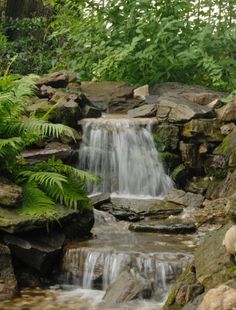 there is a waterfall in the middle of some rocks and plants on the side of it