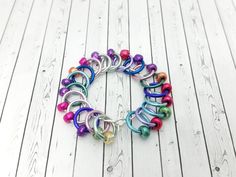 a multicolored bracelet is on a white wooden floor with beads and chains around it