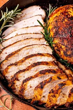 pork roasting in a cast iron skillet with rosemary sprigs on the side