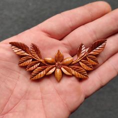 a small wooden brooch in the palm of someone's hand