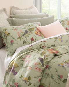 the comforter is made up with flowers and leaves on it, along with two pillows