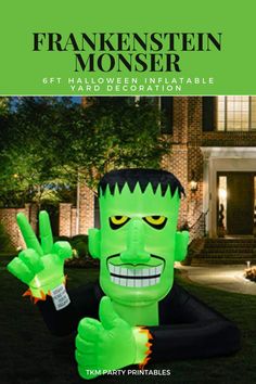 an inflatable green monster is sitting on the lawn with his hand up and two fingers