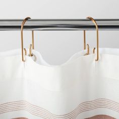 a white curtain with gold hardware hanging on a rod