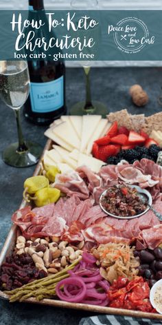 an assortment of meats and cheeses on a platter with wine in the background