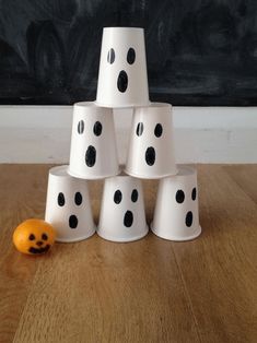 a stack of white cups sitting on top of a wooden table next to an orange