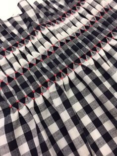 a black and white checkered fabric with red stitching on the bottom half of it