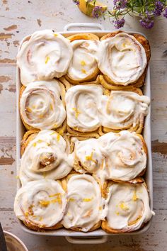 a pan filled with lemon rolls covered in icing on top of a wooden table