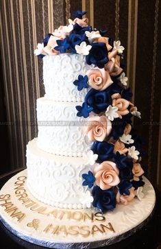 a three tiered wedding cake with blue and pink flowers