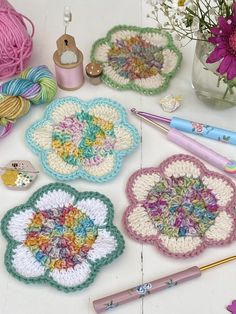 several crocheted doily are arranged on a table with yarn, scissors and flowers