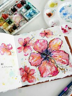 an open book with watercolor paints and flowers on it