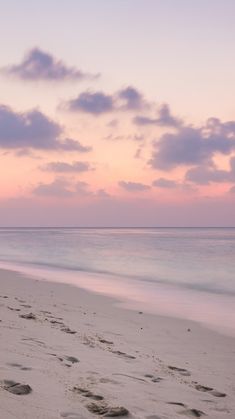 footprints in the sand on a beach at sunset