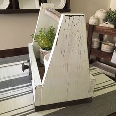 a white wooden box sitting on top of a table next to a potted plant