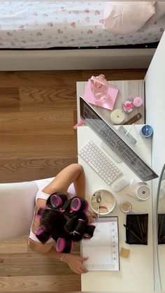 a woman sitting at a desk in front of a laptop computer with curlers on her hair