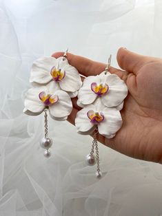 "Long white orchid earrings with pearls for every lovely day. Also, will be a perfect addition to a bride. The life of real orchids is too short of making some flower earrings with them. Instead of real flowers, I offer you these beautiful handmade flowers that will never fade. Such a piece of floral jewelry can please you for many years. They will beautifully adorn your look in any season of the year. The white orchid signifies innocence. It is often used in the bride's bouquet. However, floris Orchid Earrings, Bride's Bouquet, Earrings With Pearls, Flower Drop Earrings, Floral Jewelry, Dope Jewelry, White Orchids, Flower Pendant Necklace, Jewelry Lookbook