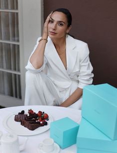 a woman sitting at a table in front of a piece of chocolate cake with strawberries on it