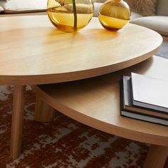 two glass vases sitting on top of a wooden table next to a book shelf