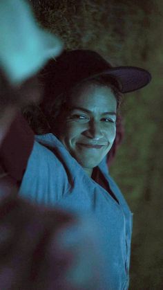 a smiling woman wearing a baseball cap in the dark