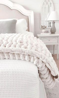 a white bed covered in blankets and pillows