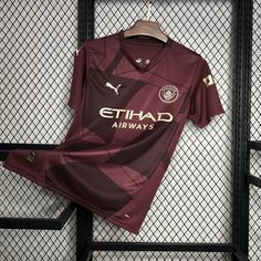 a soccer jersey is hanging on a rack in front of a chain link fence, with the name ethadd airways printed on it