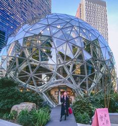 a woman standing in front of a building with a large glass dome on it's roof